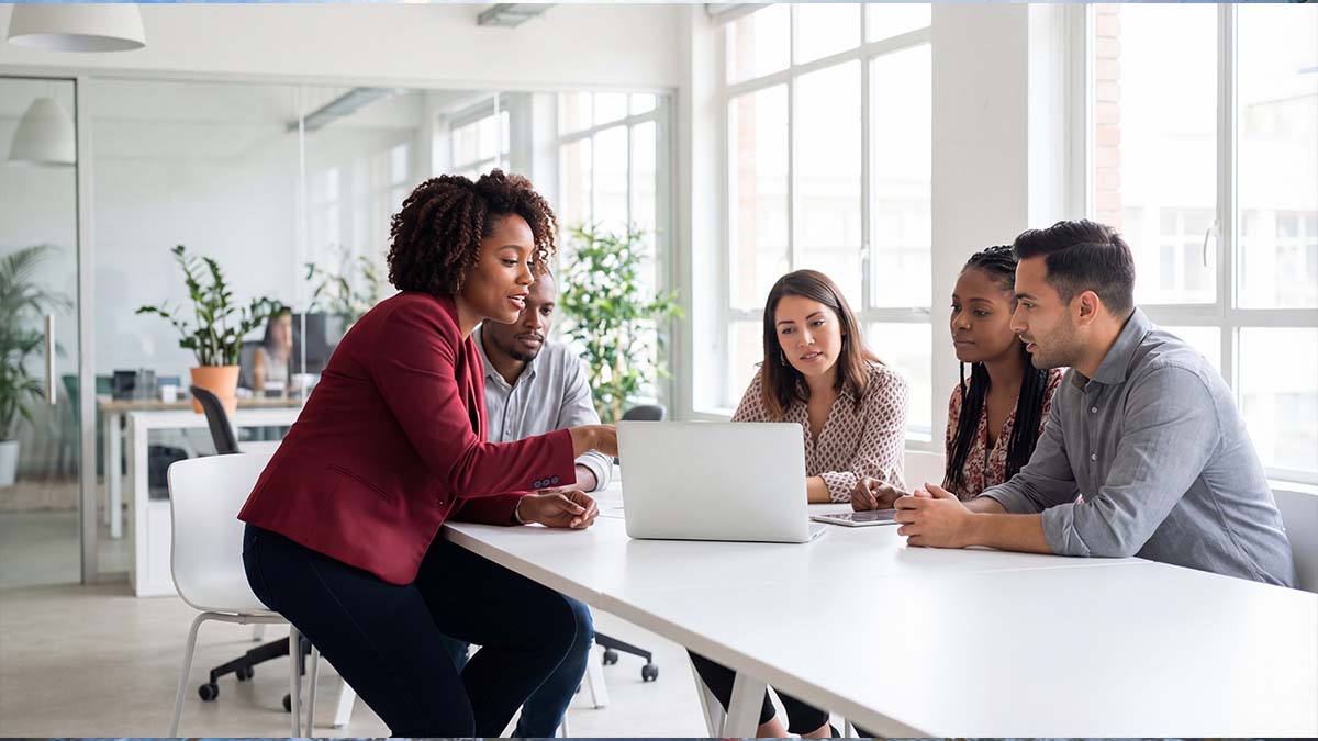 business professionals at a desk collaborating around a laptop